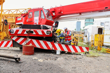 Foreman oversees work maintenance supervise workers during crane inspection by checking vehicle's...