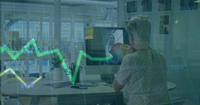 Discussing mature woman gesturing at pie chart on monitor at modern office desk, with grid overlay