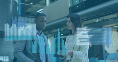 Reviewing mid adult colleagues analyzing holographic bar graphs in office atrium, with tablet
