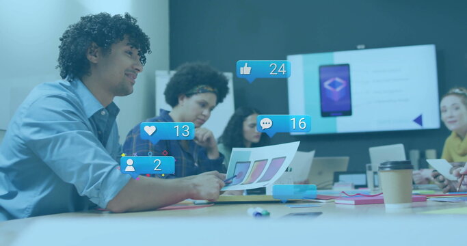 Pointing designer wearing blue shirt holding swatches at office table with digital metrics overlays