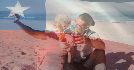 Senior couple holding fruit cocktails and raising star-shaped ornament on shore at water's edge