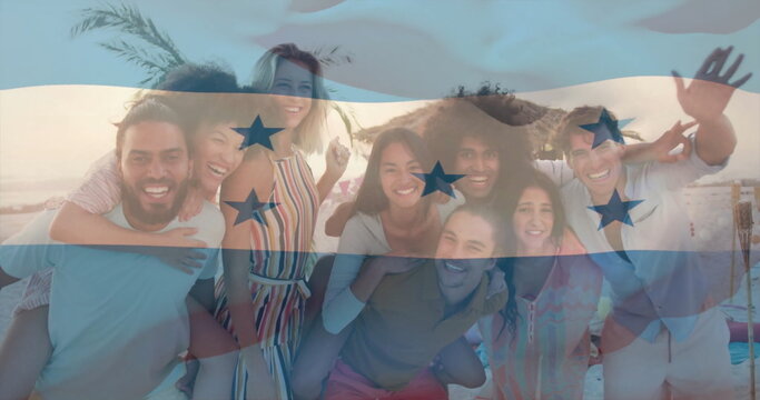 Posing group of eight friends laughing on sandy beach at sunset under straw umbrella, palm fronds