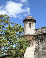 Colonial watchtower against green foliage and a bright caribbean sky in Havana.