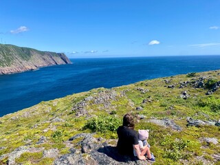 A mother and daughter enjoying the beautiful view of Logy Bay, outside St. John's newfoundland, on a beauty sunny summer day with the ocean sparking in the distance