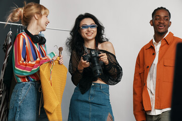 Young adult woman with camera socializing with colleagues and friends in a casual workplace, showcasing Gen Z coworkers working together and enjoying business interaction.
