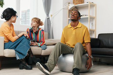 young adult colleagues socializing and working in a casual workplace with woman and man relaxing...