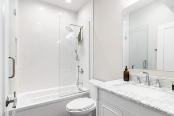 Naklejka na ściany i meble A bathroom with a white cabinet and marble countertop, marble tiled shower, and tan walls.