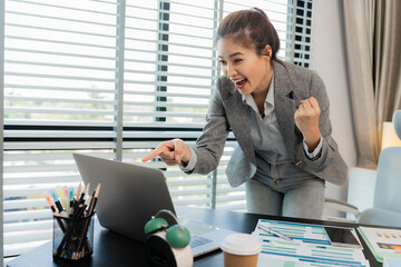 Happy Asian businesswoman celebrating victory and success of positive economic growth results,...