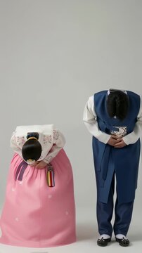 Korean couple in traditional hanbok bowing together for Chuseok holiday, formal greeting in studio setting. a person in a hanbok