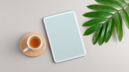White Tablet with Blank Screen Mockup, Tea Cup and Green Leaf on Neutral Background