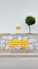 Yellow Bench Against a Stone Wall with a Small Green Tree