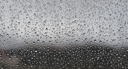Fototapeta premium Water droplet texture rainy window transparent surface with blurred natural outdoor background weather mood condensation closeup
