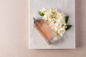 A tall elegant bottle of perfume, cosmetic spray, cologne lies on a piece of marble with numerous...