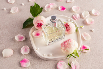 A chic bottle of women's perfume with a delicate floral aroma of rose stands on a white tray with...