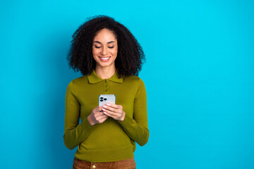 Charming Young Woman Holding a Smartphone Against a Bright Blue Background Showing Happy and...