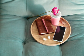 Wooden Tray with Notebook, Pen, Smartphone and Drink on Sofa. Relaxing Leisure with Digital Media...