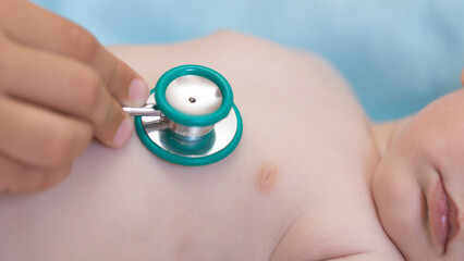 Close-up view of a pediatrician with a stethoscope examining a baby. Selective focus and blurred...