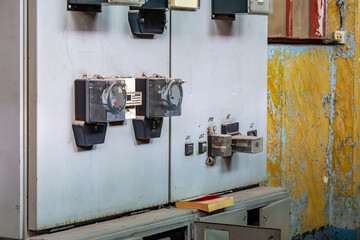 old electrical cabinet with analog electricity meters and fuses, mounted against a wall with...