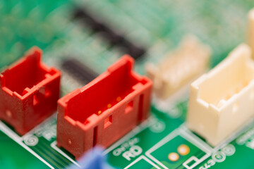 Macro shot of colorful electronic connectors, including red and white plastic sockets, mounted on a...