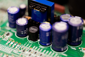 Close-up shot of a green electronic circuit board featuring several blue cylindrical capacitors and...