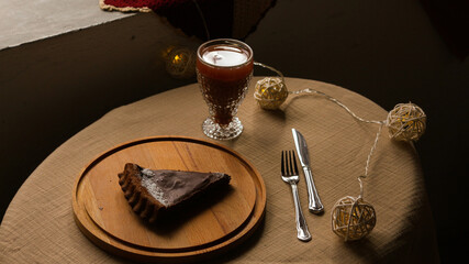 Slice of chocolate tart served with sherbet drink on cozy evening table