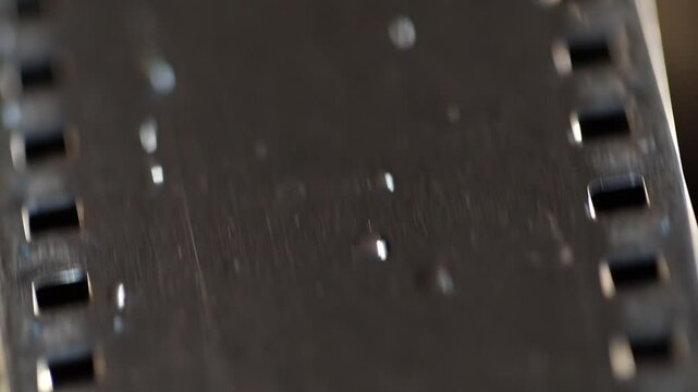 Dramatic close-up of a vintage film reel rotating and unwinding, bathed in striking red light. Perfect for cinematic, nostalgic, or artistic projects, evoking classic movie themes and atmosphere.
