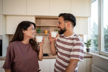 Happy couple drinking milk in modern kitchen