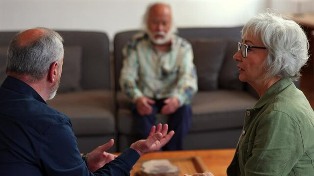 Mature married partners discussing relationship challenges with professional therapist during intimate counseling session, sitting together in comfortable living room environment