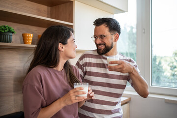 Happy couple enjoying milk in kitchen: promoting healthy lifestyle