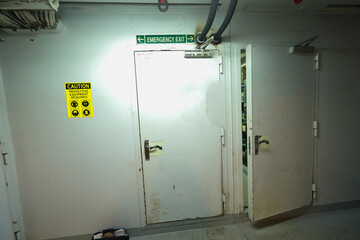 Cruise ship engine room interior with water tight doors electrical and diesel engines, water pipes, measuring instruments, warning signs