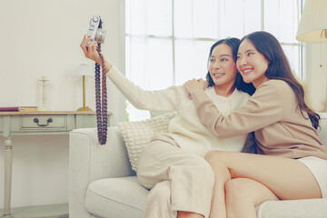Two female buddies, close friends, use a vintage camera to take pictures themselves having fun on...