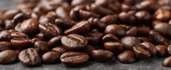Obraz premium The rich texture of freshly roasted coffee beans piled on a dark surface.