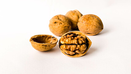 Close-up of whole and cracked walnuts on a white background, showcasing the texture and detail of the nut inside its shell, ideal for healthy food and organic ingredient concepts.