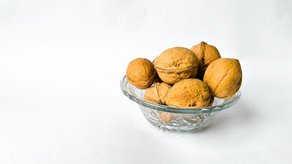 Pile of unshelled walnuts on white studio background with generous negative space, minimal food concept emphasizing healthy organic snack ingredients.