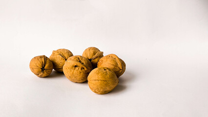Pile of unshelled walnuts on white studio background with generous negative space, minimal food concept emphasizing healthy organic snack ingredients.