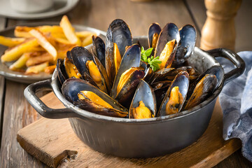 A delicious serving of cooked mussels, accompanied by golden crispy fries, evoking indulgence