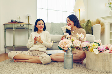 Free day lifestyle activity arranging artificial flowers at home between two asian women arranging...