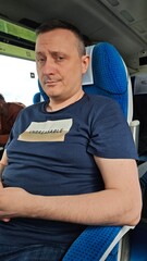 A man sitting in a modern train seat with a skeptical expression, wearing a shirt that says Unbreakable. The image reflects the concept of resilience and travel in everyday life.