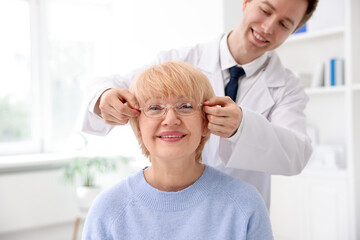 Obraz premium Ophthalmologist giving glasses to patient in clinic, closeup