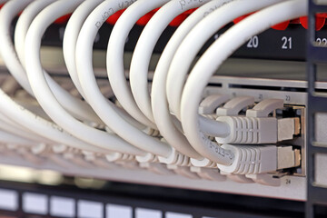 An Ethernet cable with an Rj45 connector connected to a digital equipment socket in a telecommunications rack of network equipment. 