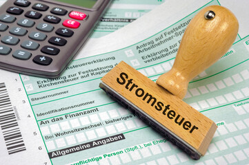 Ein Holzstempel ist beschriftet mit dem Aufdruck Stromsteuer