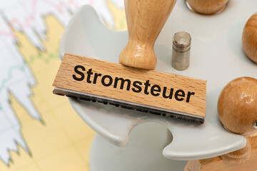 Ein Holzstempel ist beschriftet mit dem Aufdruck Stromsteuer