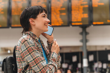 Young woman enjoying a phone conversation while waiting at a bustling transportation hub during daytime