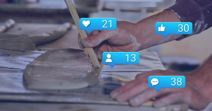 Craftsman brushing clay slip across slab, reaction icons rising showcasing marketing engagement
