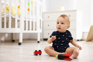 Cute little baby playing with toys in room, space for text