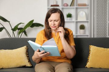 Woman with vision problem reading book on sofa at home