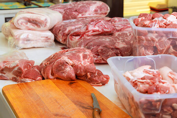 Various cuts of pork are arranged on wooden surface in butcher shop, highlighting fresh produce...