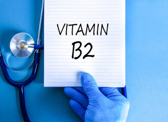 Vitamin B2 riboflavin symbol. Concept words Vitamin B2 on beautiful white note. Doctor's hand in...