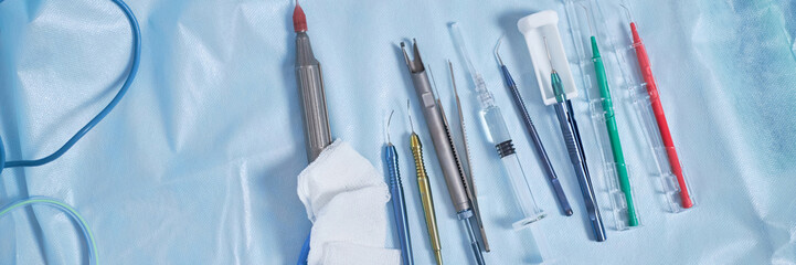 Surgical instruments arranged on sterile drape in operating room including electrosurgical pencil,...
