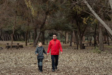 papá e hijo caminando juntos de la mano por un camino otoñal